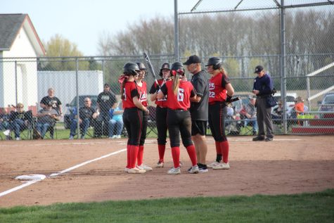 Varsity Softball starters with head coach in a huddle mid game.