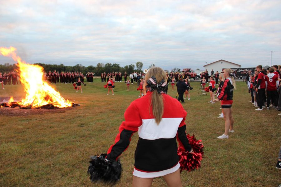 The cheer team and band perform as the fire burns.