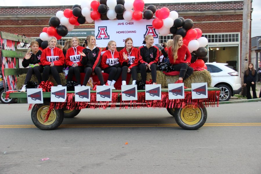 The Jonathan Alder cheerleaders smile as they ride  by the parade onlookers.