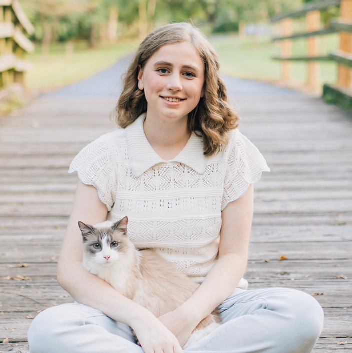 Olivia Cramer poses for a photo with a cat in her lap.