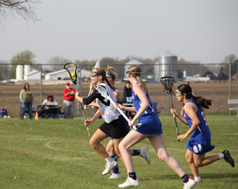 Junior Norah OConnor sprints to home goal with ball in lacrosse stick. 
