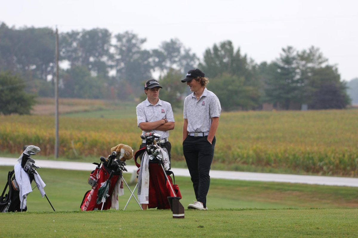 Seniors Brady Fox and Cameron Potter converse while Hilliard Davidson take their shots. Fox says his favorite golf memory is, When I shot the school record just a few weeks ago with a 31 for nine holes.