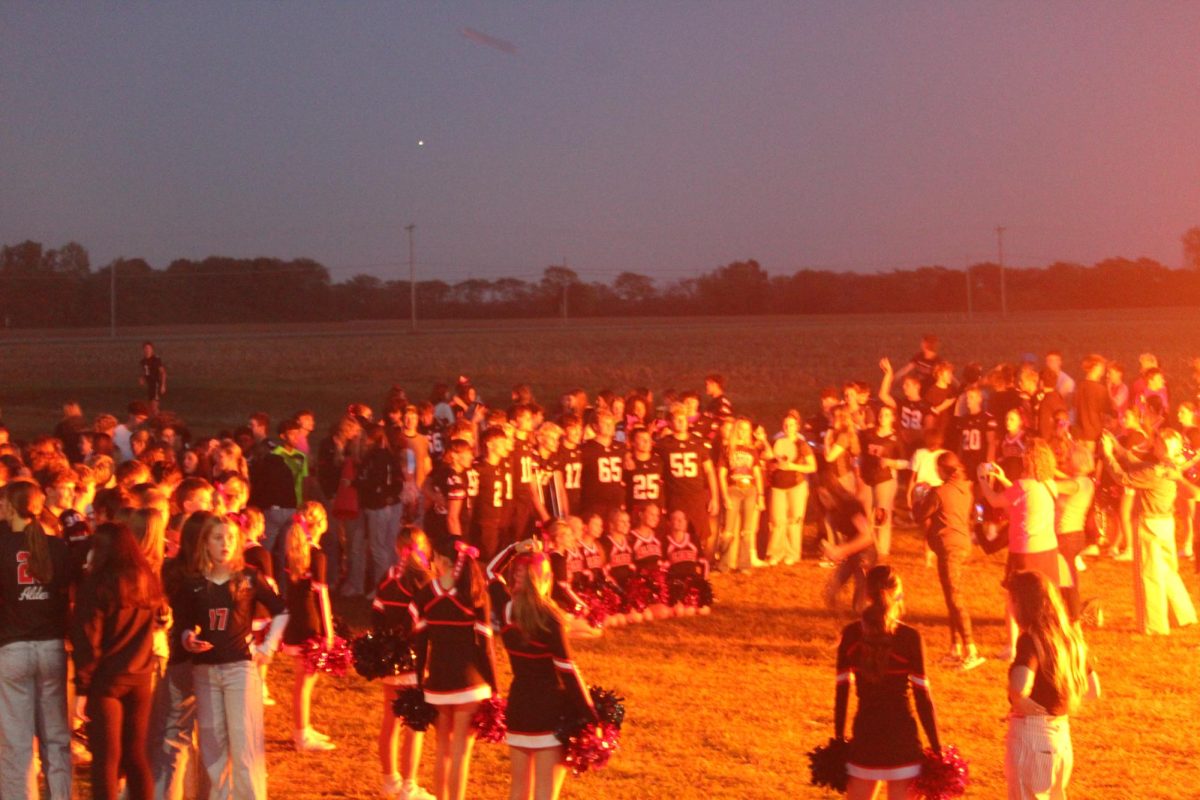 The football and cheer lead seniors to pose for a group photo in the light of the bonfire. 