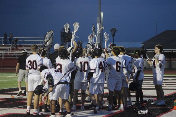 The Jonathan Alder boys lacrosse team raises their sticks before the second half starts.